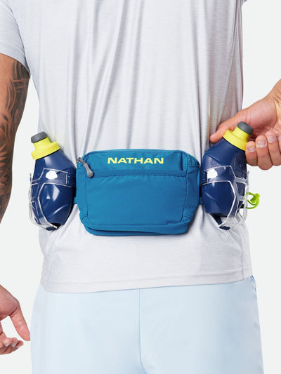 color:Deep Blue/Safety Yellow||seo:Nathan TrailMix Plus Hydration Belt 3.0 - Deep Blue/Safety Yellow - On Model - Pulling Flask From Carrier