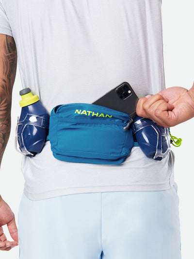 color:Deep Blue/Safety Yellow||seo:Nathan TrailMix Plus Hydration Belt 3.0 - Deep Blue/Safety Yellow - On Model - Pulling Cell Phone From Pocket