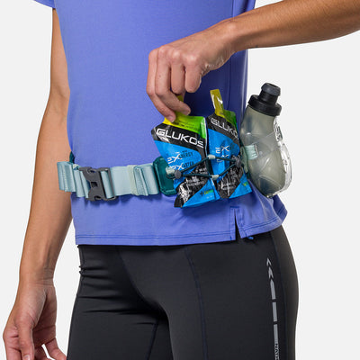 color:Deep Teal/Finish Lime||seo:Nathan TrailMix Plus Hydration Belt 3.0 - Deep Teal/Finish Lime- On Model - Detail View of Elastic Keepers Holding Glukos Energy Gels and Hydration Flask