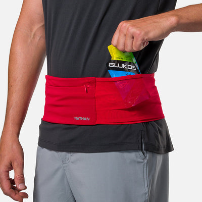 color:Ribbon Red/Reflective Silver||seo: Nathan Zipster Max Training Waist Belt - Ribbon Red/Reflective Silver - Model Pulling Glukos Energy Gel (Lemon Lime Flavor) out of Side Storage Pocket