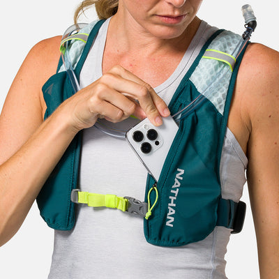 color:Deep Teal/Reflective Silver||seo:Nathan QuickStart 3.0 4 Liter Hydration Pack - Deep Teal/Reflective Silver - On Model - Model Pulling iPhone From Front Zippered Pocket