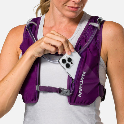 color:Imperial Purple/Reflective Silver||seo:Nathan QuickStart 3.0 4 Liter Hydration Pack - Imperial Purple/Reflective Silver - On Model - Model Pulling iPhone From Front Zippered Pocket