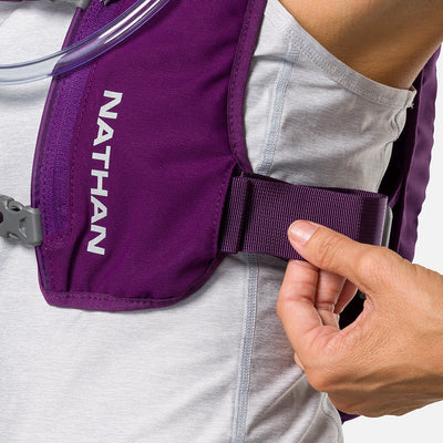 color:Imperial Purple/Reflective Silver||seo:Nathan QuickStart 3.0 4 Liter Hydration Pack - Imperial Purple/Reflective Silver - On Model - Closeup Detail View of Model Adjusting Wide Side Straps For a Secure No Bounce Fit