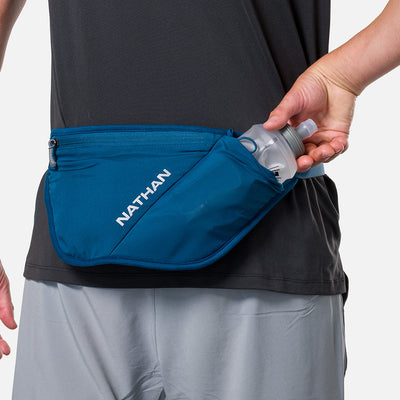color:Sailor Blue/Reflective Silver||seo:Nathan Pinnacle FeatherLite Unisex Hydration Waist Belt - Sailor Blue/Reflective Silver - Model Pulling 18oz Flask from Pouch