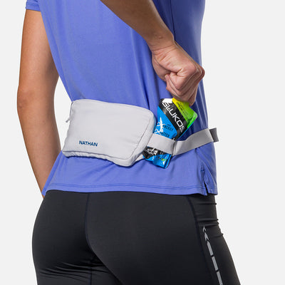 color:Vapor Grey/Sailor Blue||seo:Nathan Marathon Waist Pack 3.0 - Vapor Grey/Sailor Blue - On Model - Pulling Glukos Energy Gel (Lemon Lime Flavor) From Keeper