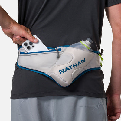 color:Vapor Grey/Sailor Blue||seo:Nathan Peak Hydration Waist Pack - Vapor Grey/Sailor Blue - On Model - Pulling Cell Phone From Zippered Pocket