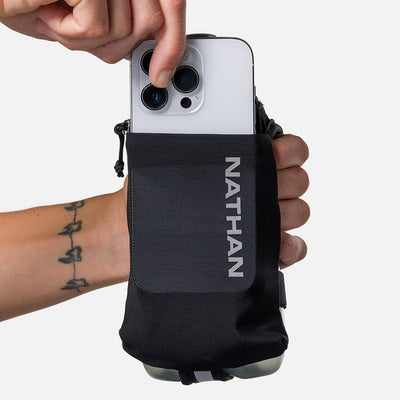 color:Black/Reflective Silver||seo:Nathan SpeedDraw 2 18oz Flask - Black/Reflective Silver - Model Pulling iPhone from Front Pouch