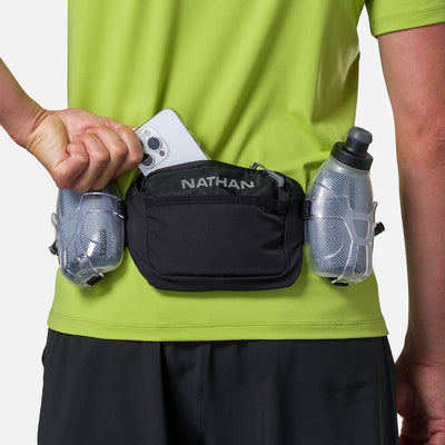 color:Black/Reflective Silver||seo:Nathan TrailMix Plus Insulated Hydration Waist Belt 3.0 - Black/Reflective Silver - On Model - Pulling Cell Phone From Pocket