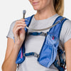 color:Periwinkle/Estate Blue||seo:Nathan TrailMix 2.0 12 Liter Unisex Hydration Pack - Periwinkle/Estate Blue - Female Runner Taking Sip of Water From Bladder Hose