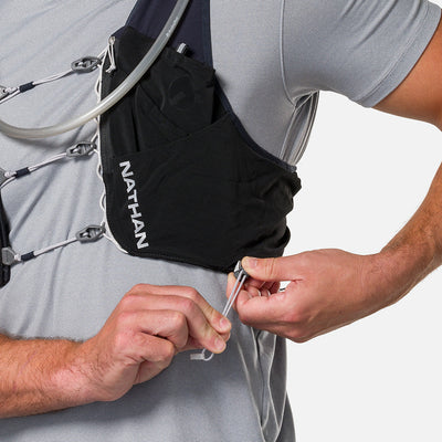 color:Black/Reflective Silver||seo:Nathan Pinnacle Pro 12 Liter Unisex Hydration Race Vest - Black/Reflective Silver - Model Adjusting QuickFit Size System to Adjust Around His Body