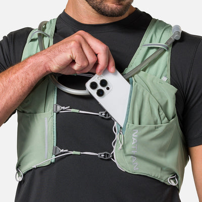 color:Sage Green/Reflective Silver||seo:Nathan Pinnacle Pro 12 Liter Unisex Hydration Race Vest - Sage Green/Reflective Silver - Male Runner Pulling Cell Phone From Front Storage Pocket