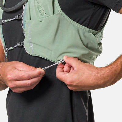 color:Sage Green/Reflective Silver||seo:Nathan Pinnacle Pro 12 Liter Unisex Hydration Race Vest - Sage Green/Reflective Silver - Model Adjusting QuickFit Size System to Adjust Around His Body