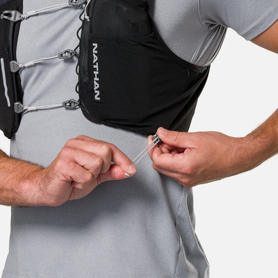 color:Black/Reflective Silver||seo:Nathan Pinnacle Pro 6 Liter Unisex Hydration Race Vest - Black/Reflective Silver - Model Adjusting QuickFit Size System to Adjust Around His Body
