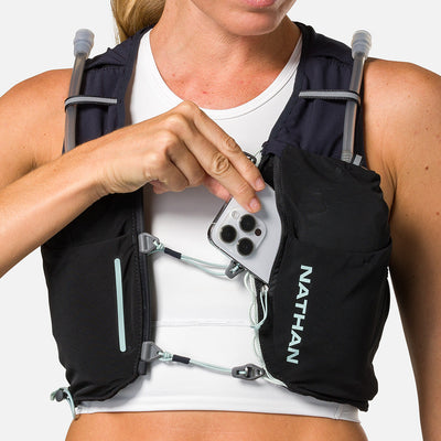 color:Black/Surf Spray||seo:Nathan Pinnacle Pro 6 Liter Women's Hydration Race Vest - Black/Surf Spray - Female Runner Pulling iPhone From Front Storage Pocket