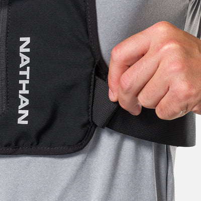 color:Black/Reflective Silver||seo:Nathan QuickStart 3.0 6 Liter Hydration Pack - Black/Reflective Silver - On Model - Closeup Shot of Model Adjusting Wide Side Straps For a Secure No Bounce Fit
