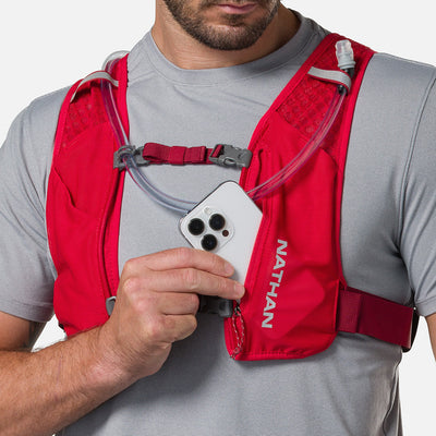 color:Ribbon Red/Reflective Silver||seo:Nathan QuickStart 3.0 6 Liter Hydration Pack - Ribbon Red/Reflective Silver - On Model - Model Pulling iPhone From Front Zippered Pocket