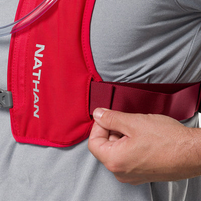 color:Ribbon Red/Reflective Silver||seo:Nathan QuickStart 3.0 6 Liter Hydration Pack - Ribbon Red/Reflective Silver - On Model - Closeup Shot of Model Adjusting Wide Side Straps For a Secure No Bounce Fit