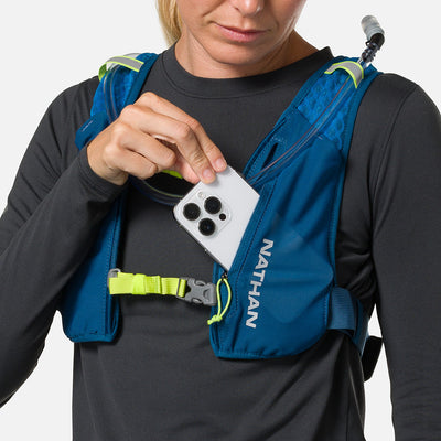 color:Sailor Blue/Reflective Silver||seo:Nathan QuickStart 3.0 6 Liter Hydration Pack - Sailor Blue/Reflective Silver - On Model - Model Pulling iPhone From Front Zippered Pocket