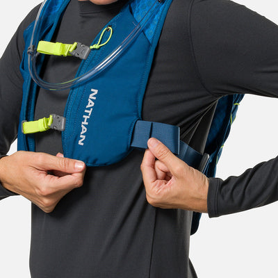 color:Sailor Blue/Reflective Silver||seo:Nathan QuickStart 3.0 6 Liter Hydration Pack - Sailor Blue/Reflective Silver - On Model - Model Adjusting Wide Side Straps For a Secure No Bounce Fit